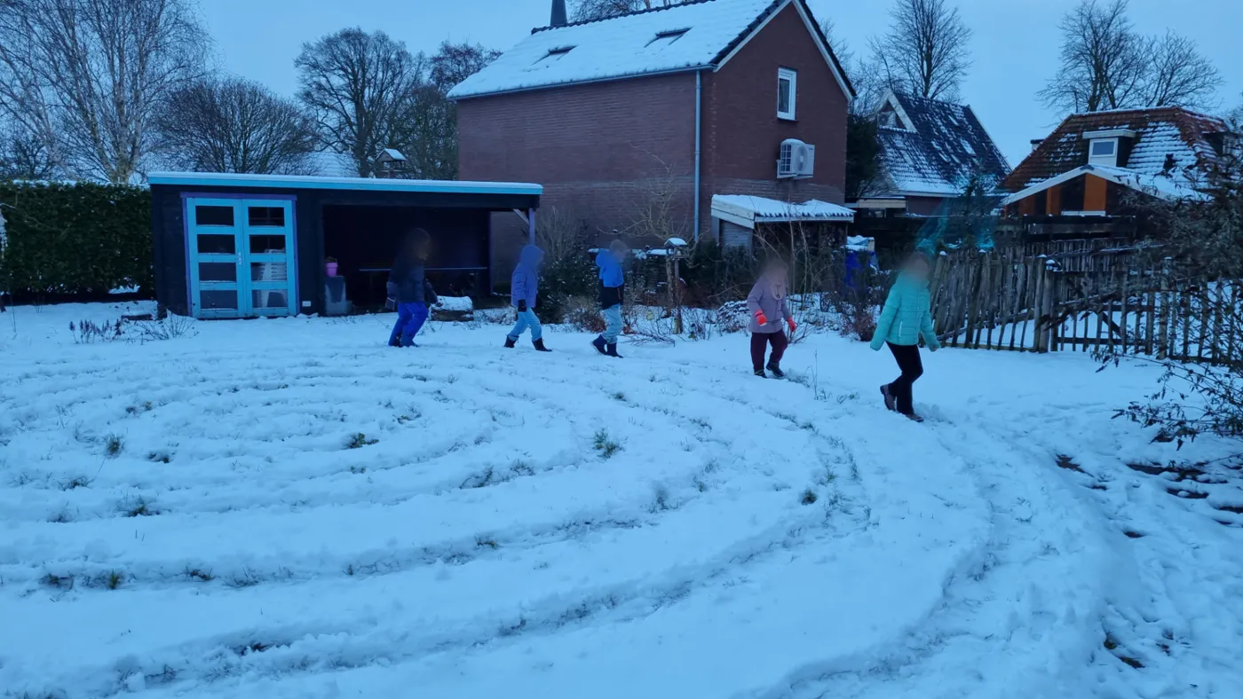 Kinderen lopen in de sneeuw een labyrintpad tijdens kinderyoga buiten in Opmeer