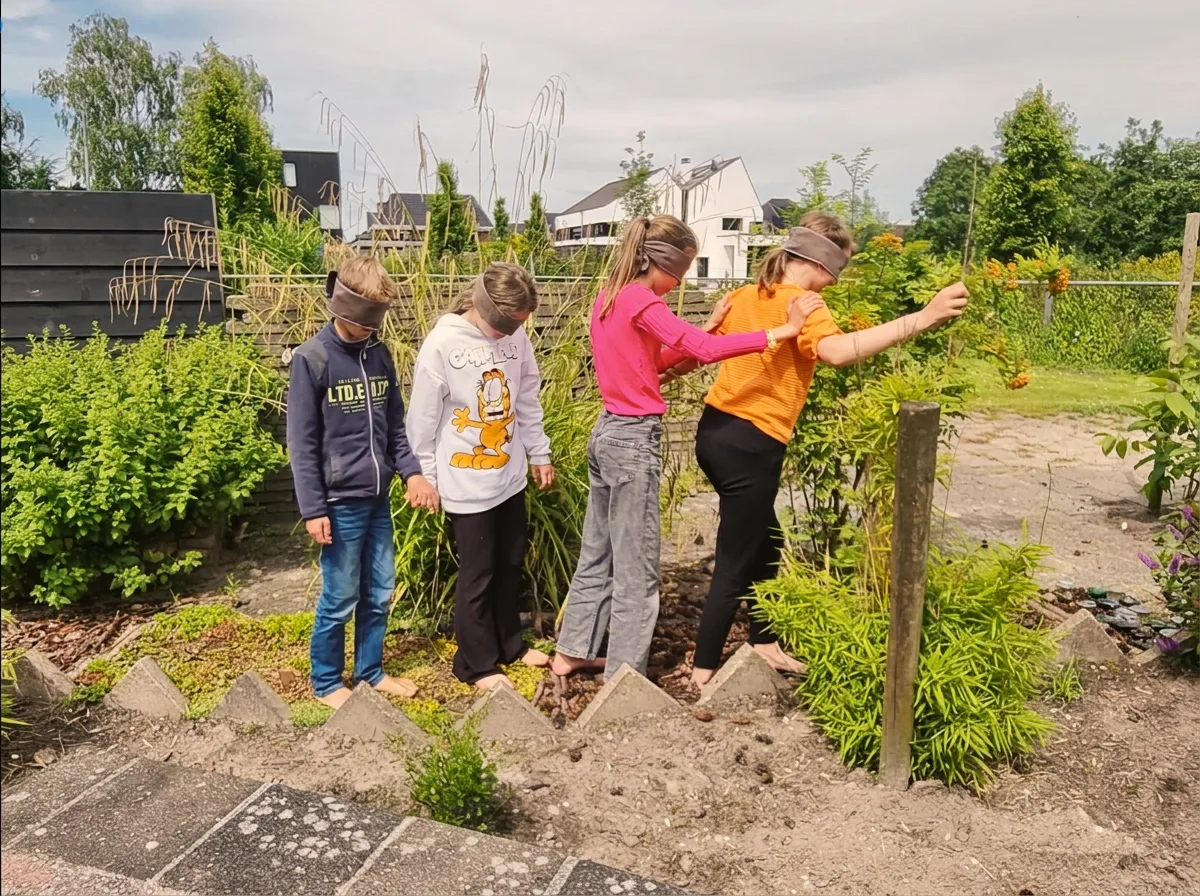 Kinderen lopen geblinddoekt over een blotevoetenpad tijdens een gastles van Kinderyoga Opmeer