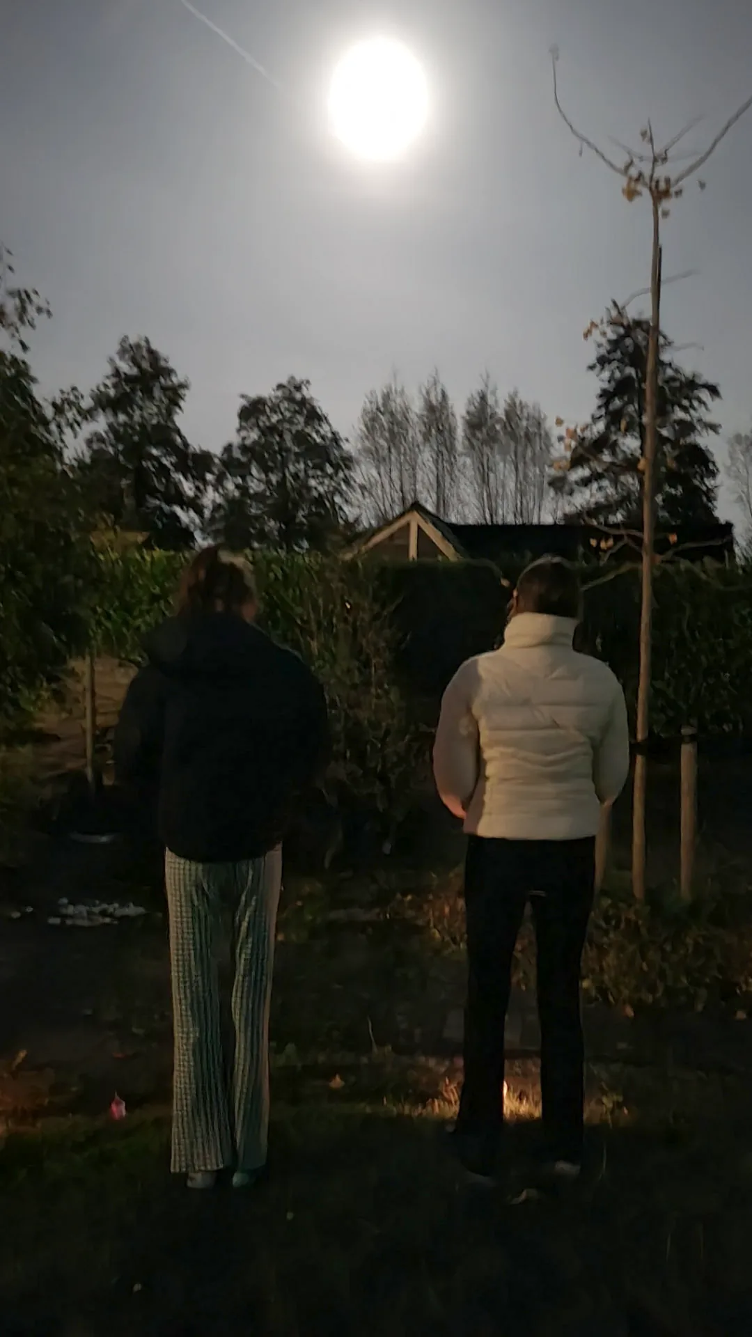 Jongeren kijken naar de maan tijdens tieneryoga buiten in het donker