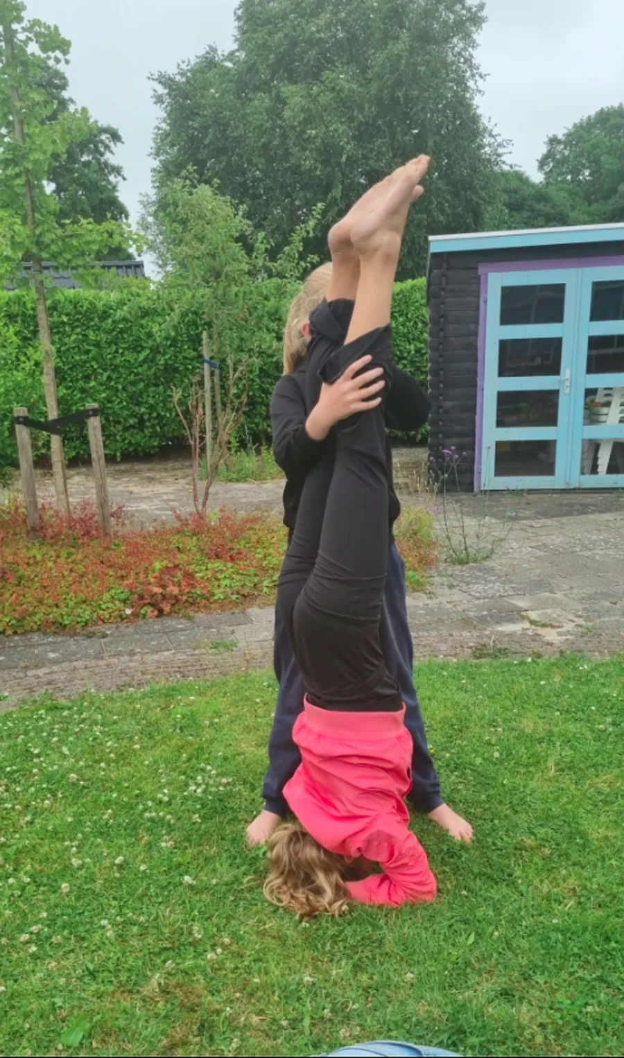 Twee kinderen helpen elkaar met een handstand tijdens kinderyoga in Opmeer